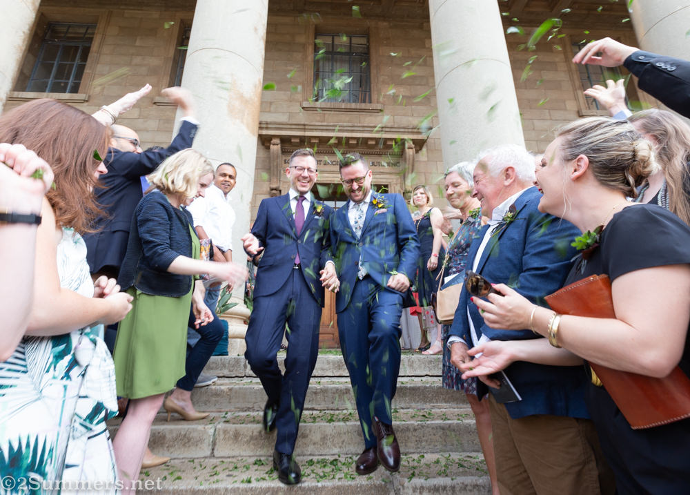Guy and Thomas walk down the stairs after getting married.
