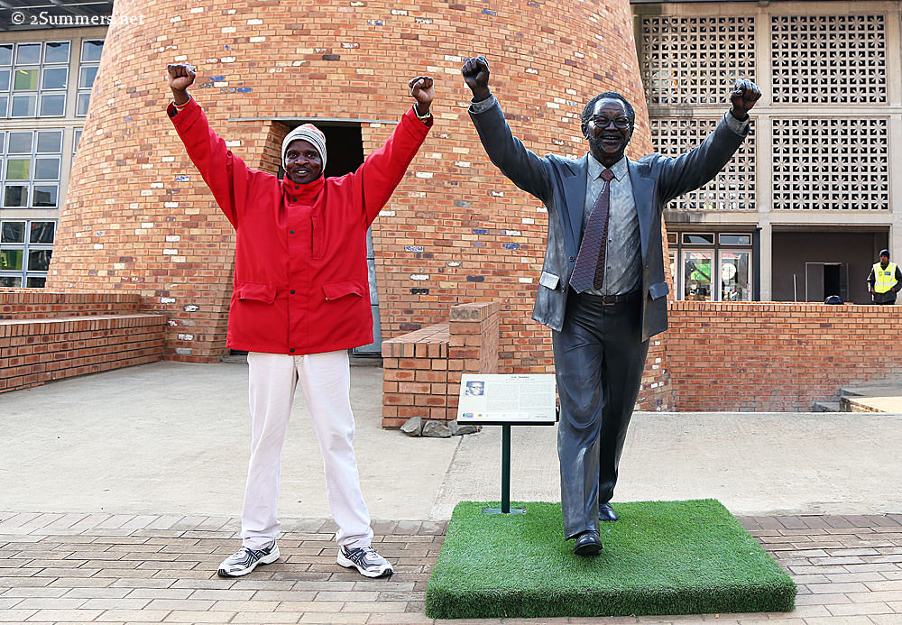 Man posing with statue of Walter Sisulu