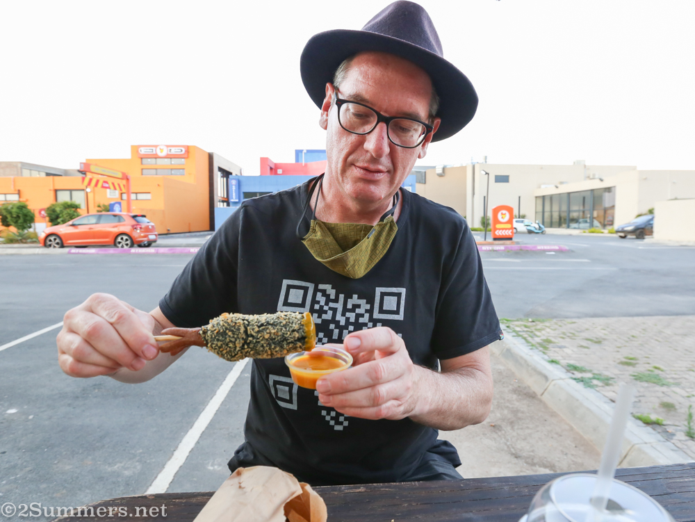Dipping squid corn dog in mustard sauce