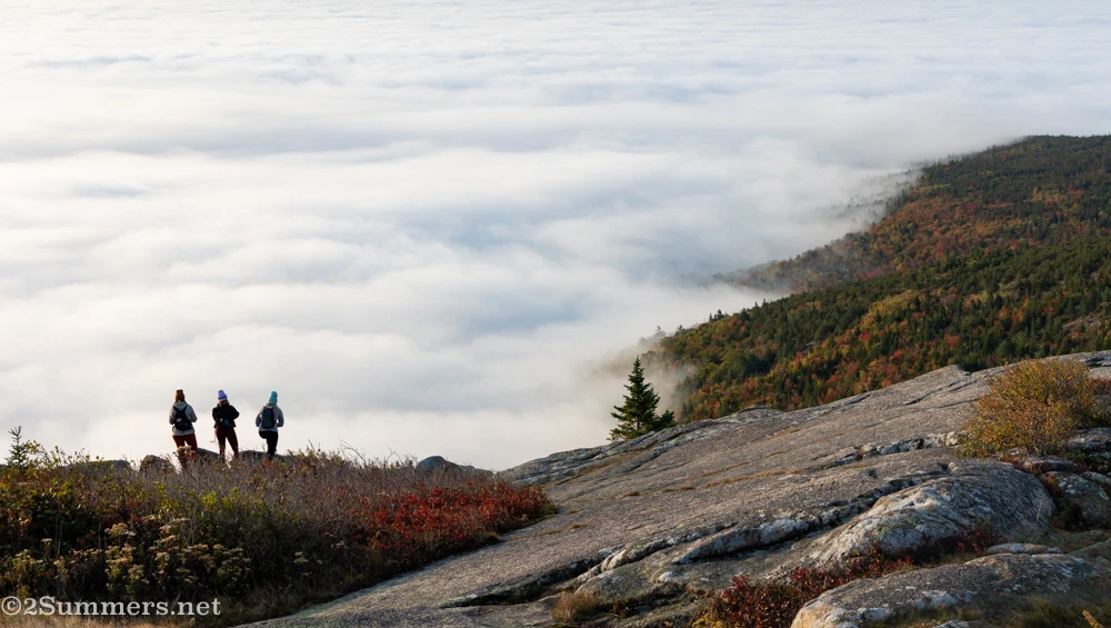 Three people standing at the top of Cadillac Mountain